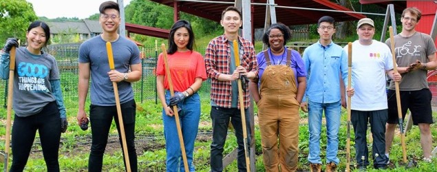 Smiling people standing with gardening equipment