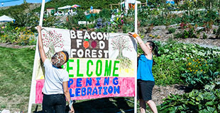 Couple of people holding up Beacon Food Forest banner
