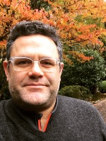 Matt smiling at the camera in a dark sweater with fall foliage in the background