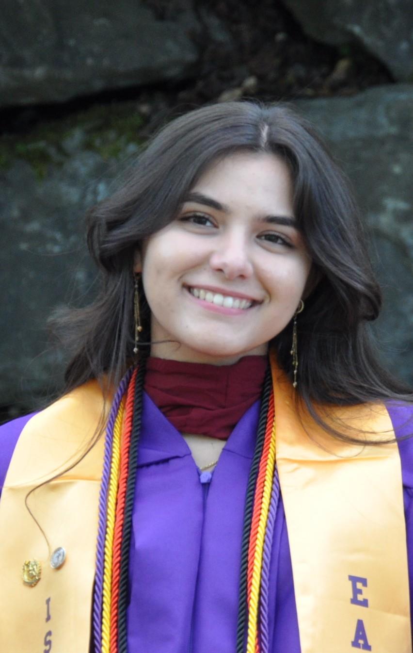 Prisha smiling outside in her graduation gown.